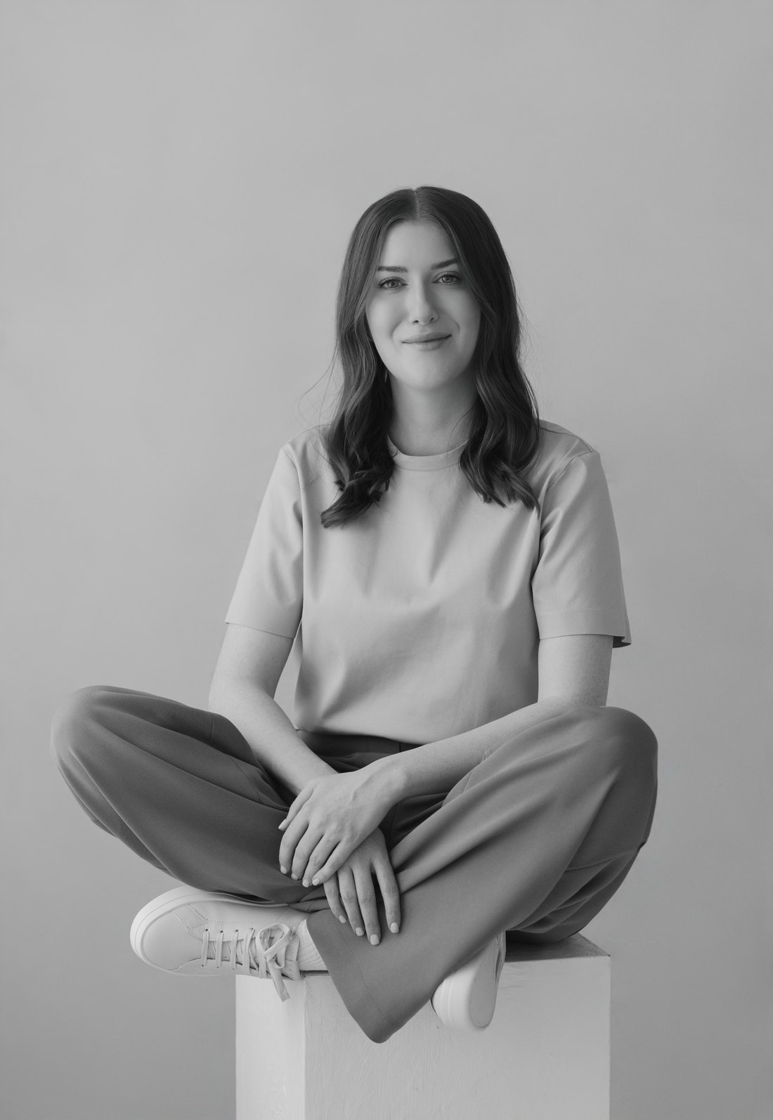 Black-and-white photo of Jackie Larkin, counsellor in Calgary, sitting cross-legged and smiling